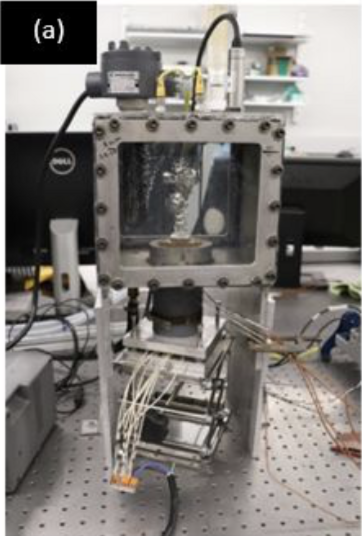 Laboratory equipment with wires and a glass chamber on a perforated table.